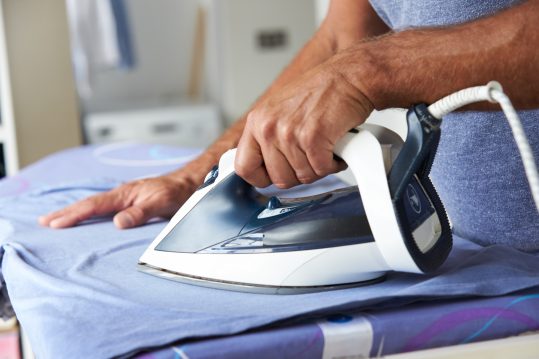 Close Up Of Man Ironing Laundry